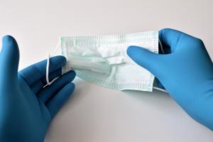 Deux mains avec des gants de chirurgie tenant un masque de chirurgien